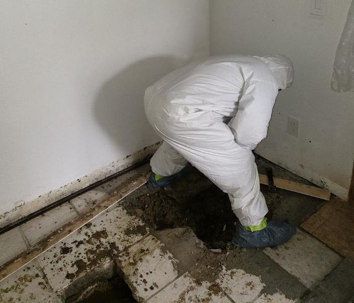 Worker bending over large hole in the floor